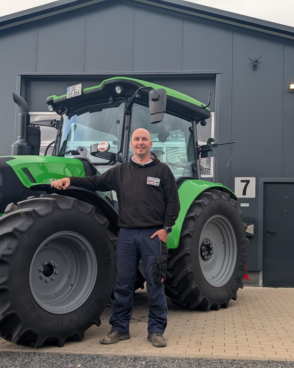 Dirk Rössler vor der Firmenhalle, neben einem Deutz-Fahr Traktor